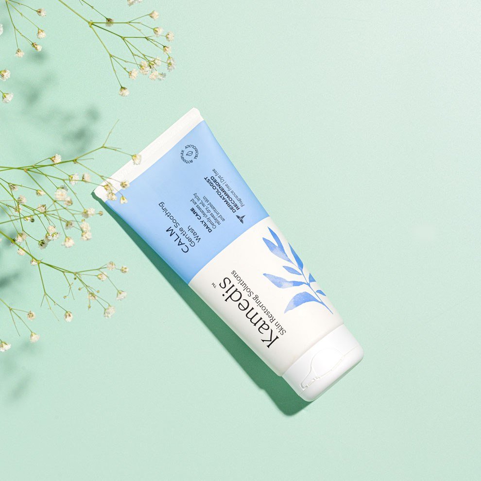 Kamedis Calm Gentle Soothing Wash, stilvoll präsentiert auf grünem Hintergrund mit dekorativen Blumen.