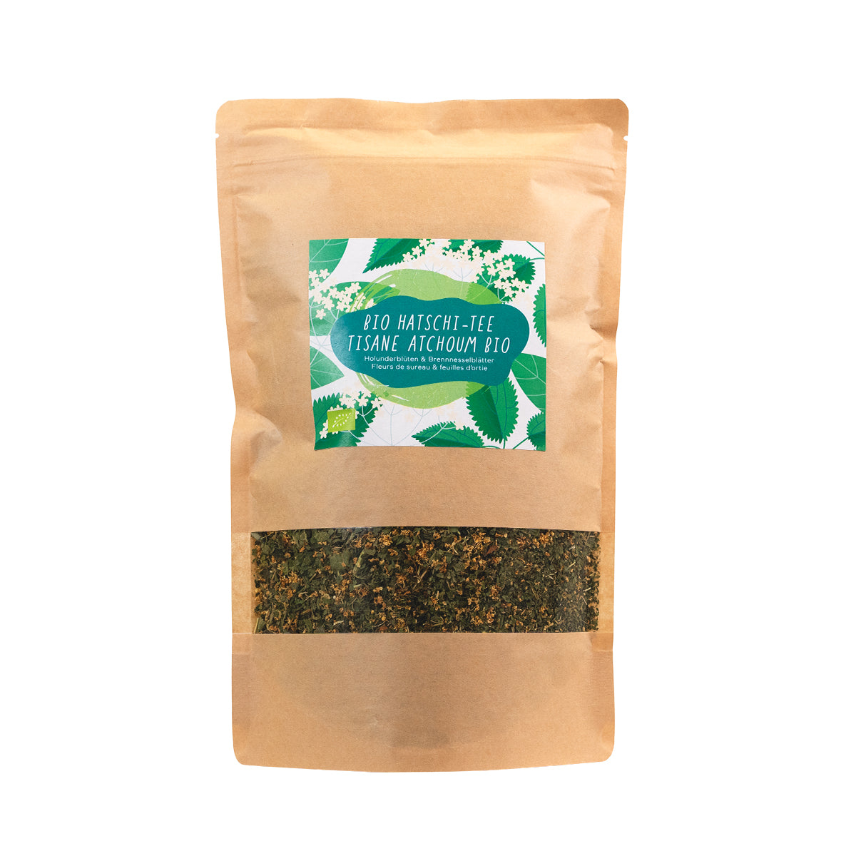 Beutel mit Bio Hatschitee, gefüllt mit einer Mischung aus getrockneten Holunderblüten und Brennnesselblättern. Etikett in Grün mit Pflanzenillustration und zweisprachiger Beschriftung.