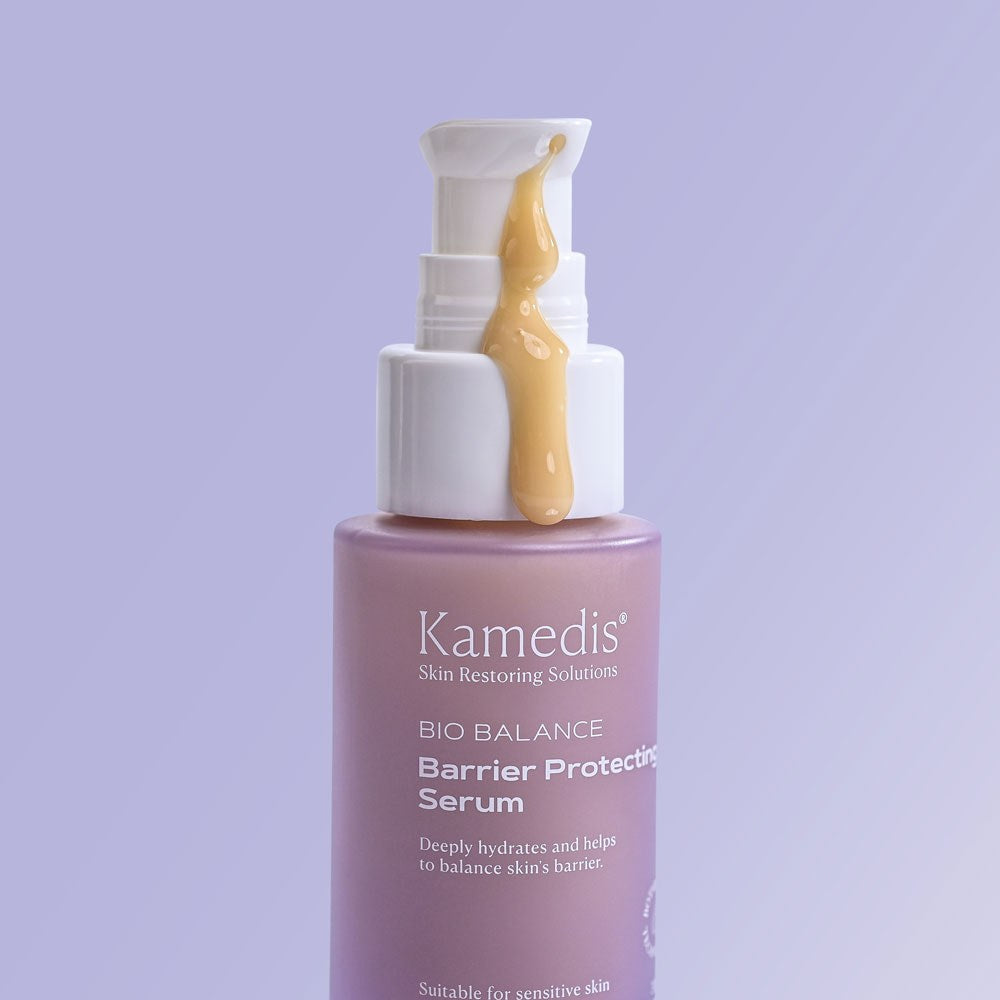 Nahaufnahme der Pumpflasche Kamedis Bio Balance Barrier Protecting Serum, aus der eine goldene Serum-Textur herausläuft.