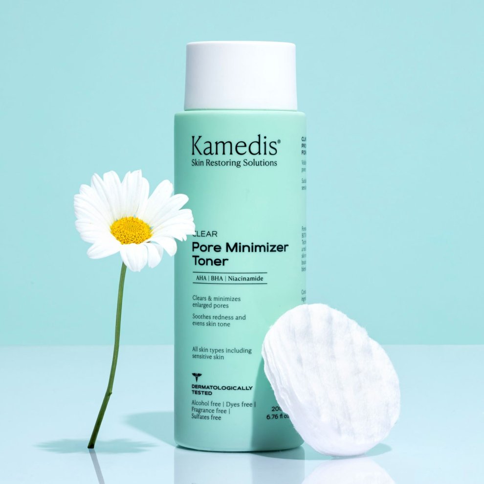 Kamedis Clear Pore Minimizer Toner in grüner Rundflasche, daneben ein Wattepad und eine weisse Blume auf blauem Hintergrund.
