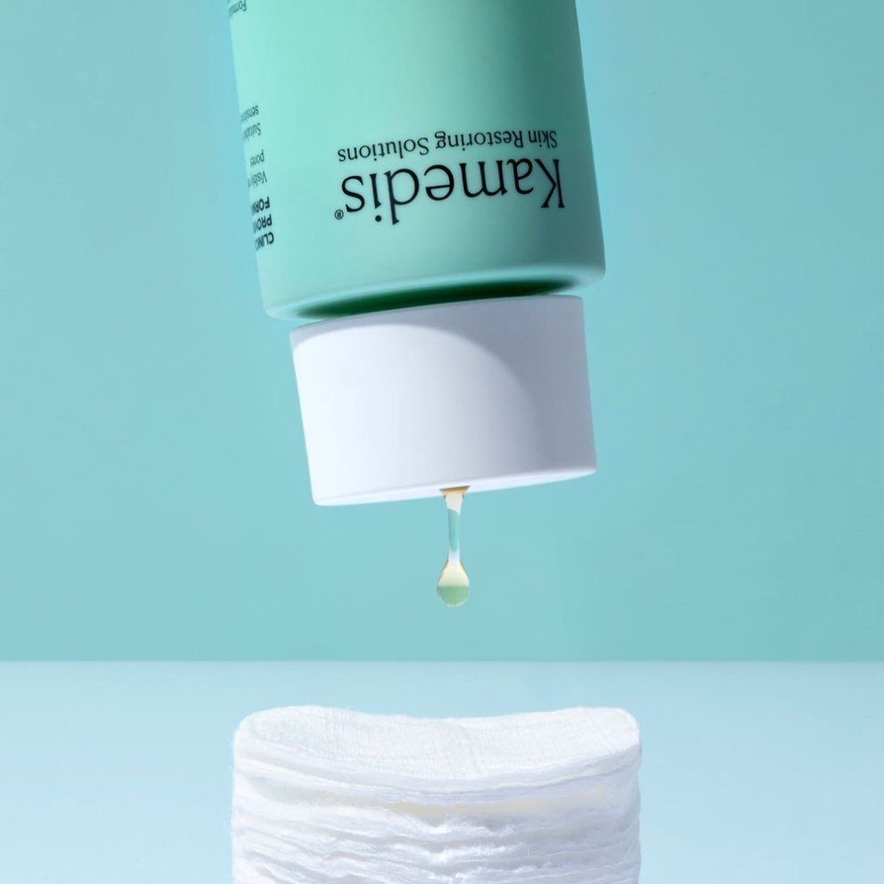 Umgedrehte Flasche Kamedis Clear Pore Minimizer Toner, aus der ein Tropfen Flüssigkeit auf ein Wattepad fällt.