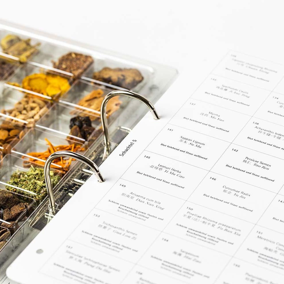 Geöffneter Ordner mit Kräuterproben und detaillierten Beschreibungen für TCM-Therapeuten.